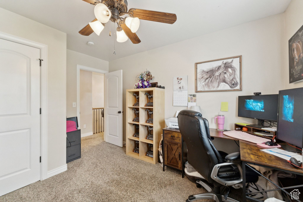 Carpeted home office with ceiling fan and baseboards