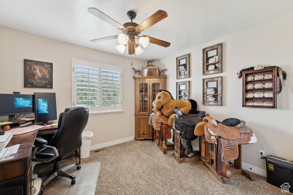 Home office featuring carpet flooring, ceiling fan, and baseboards