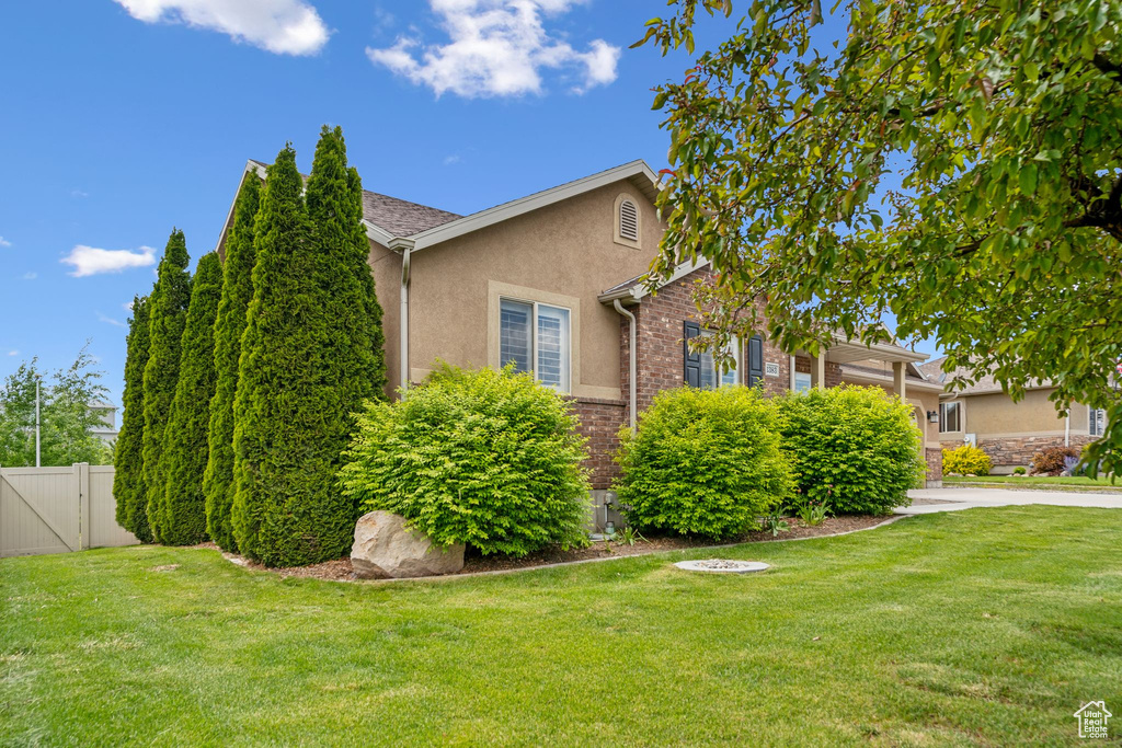 View of side of property with stucco siding, a gate, driveway, and a garage