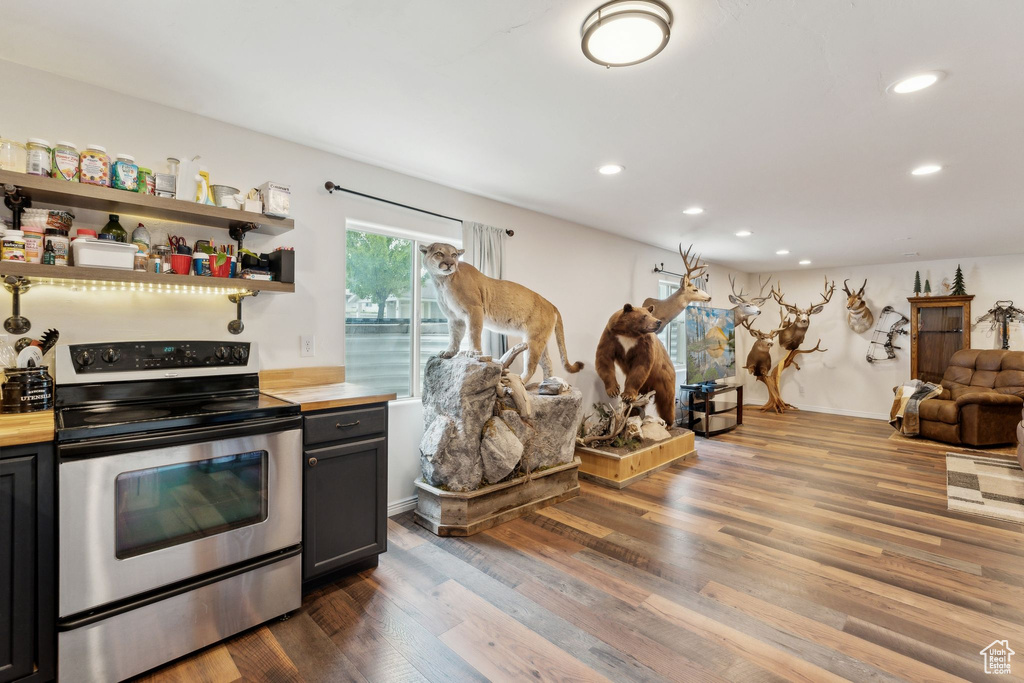 Kitchen featuring stainless steel electric stove, recessed lighting, butcher block counters, dark wood-type flooring, and open floor plan