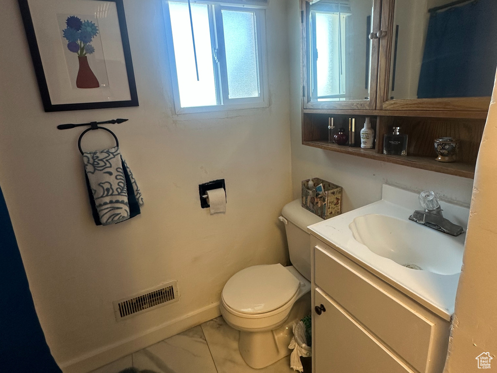Bathroom featuring marble finish flooring, toilet, and vanity