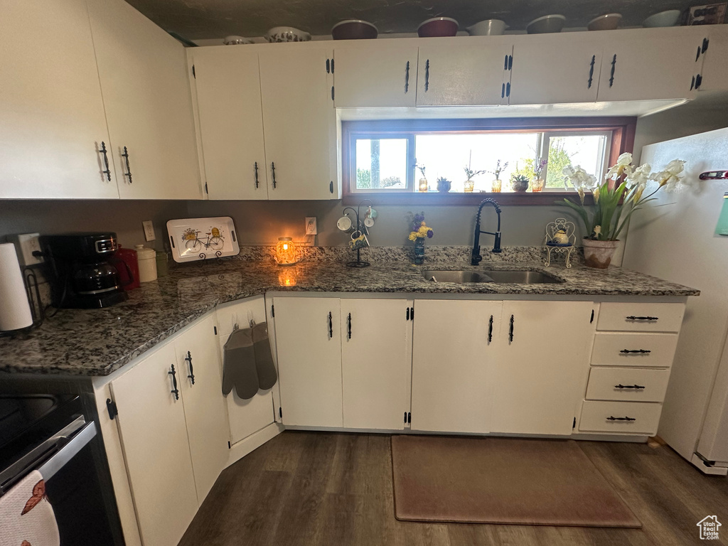 Kitchen featuring a sink, dark wood-type flooring, dark stone counters, and healthy amount of natural light