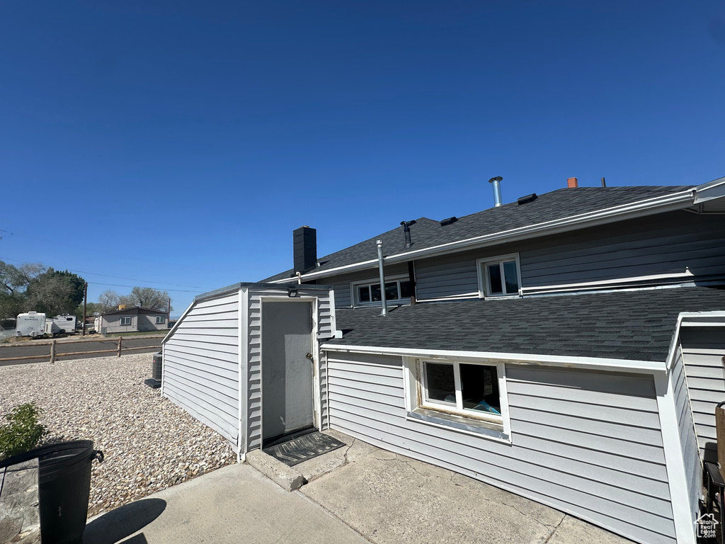 Back of house with a patio, a chimney, and roof with shingles