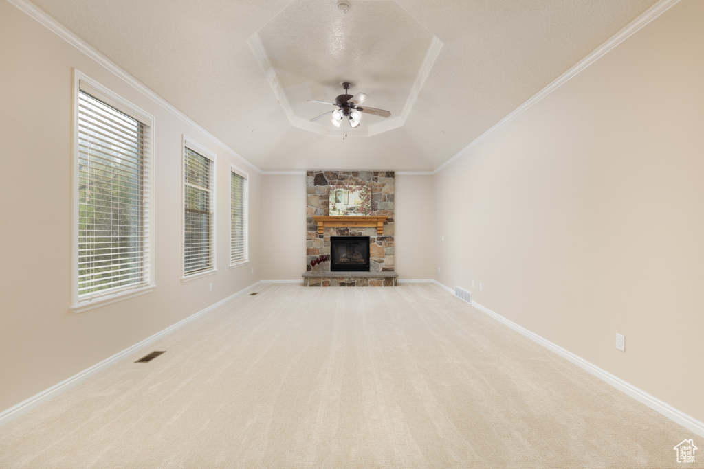 Unfurnished living room with a tray ceiling, ceiling fan, light carpet, a fireplace, and healthy amount of natural light