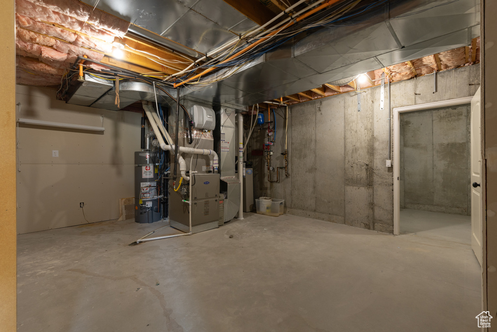 Unfinished basement featuring water heater and heating unit