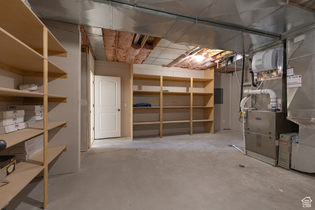 Unfinished below grade area with electric panel and heating unit