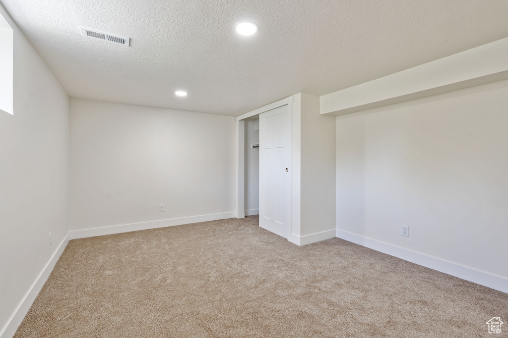 Basement with carpet flooring, a textured ceiling, baseboards, and recessed lighting