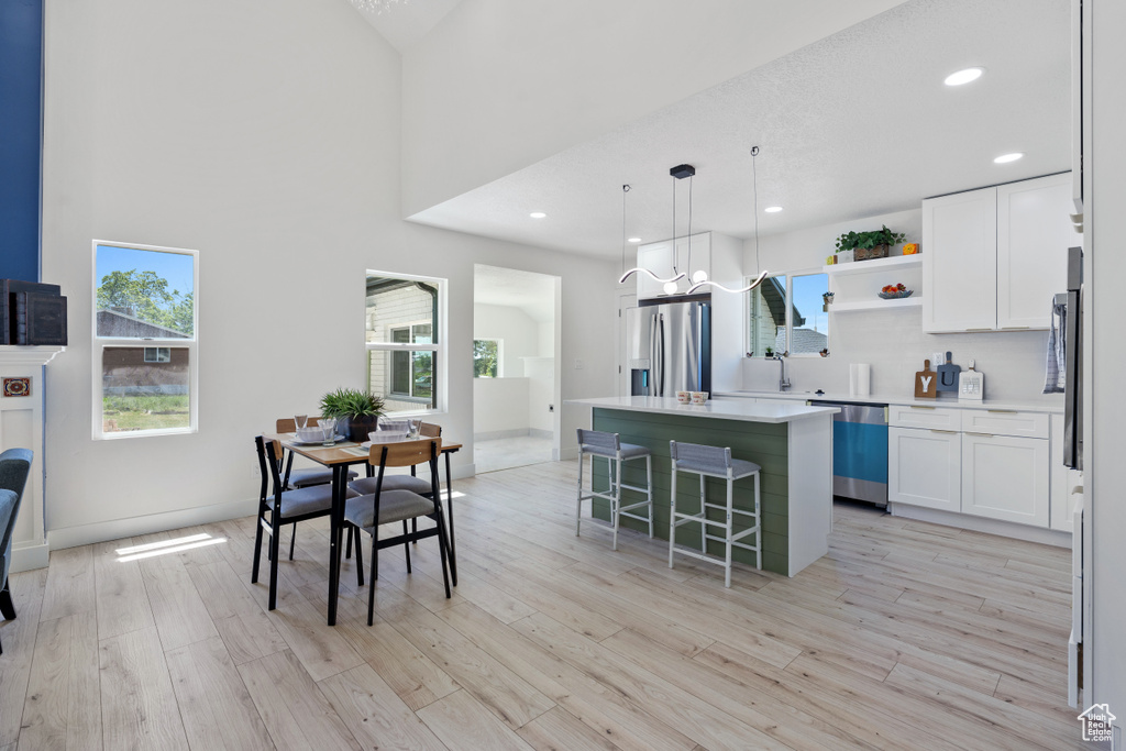 Kitchen with stainless steel appliances, healthy amount of natural light, a kitchen island, open shelves, and recessed lighting