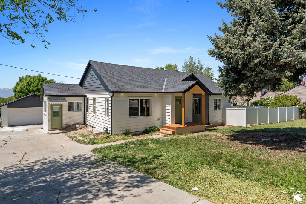 View of front of home featuring an outdoor structure, a shingled roof, and a garage