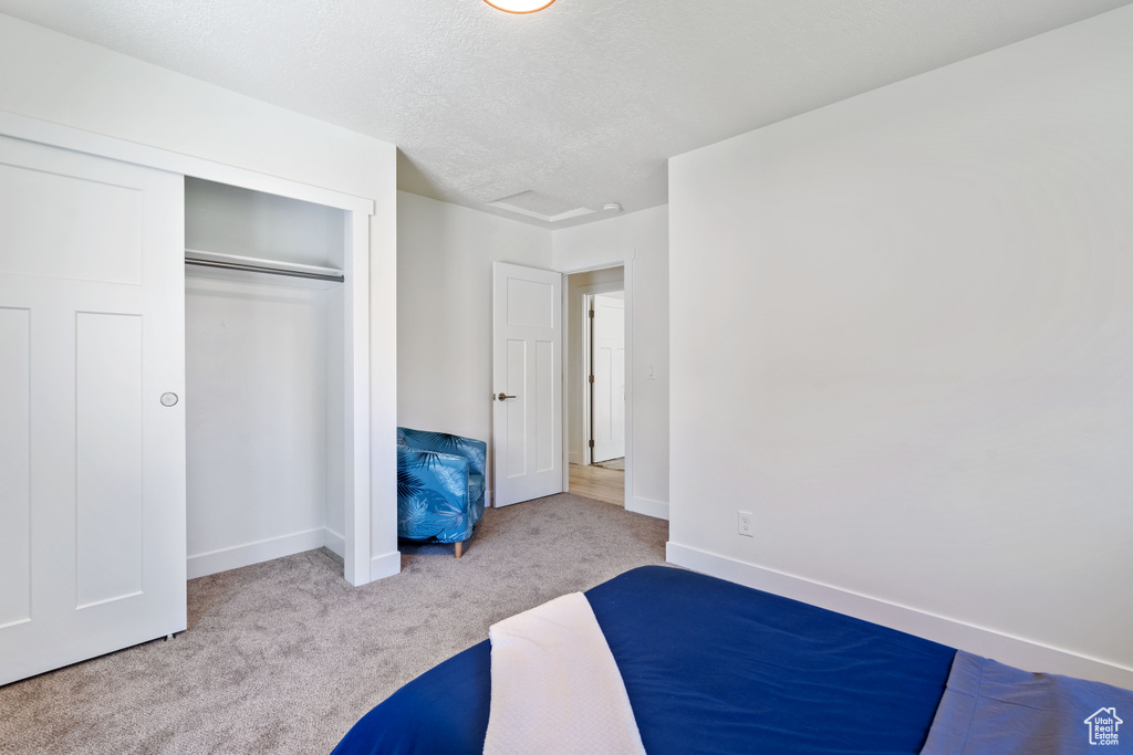 Unfurnished bedroom with carpet, baseboards, a closet, and a textured ceiling