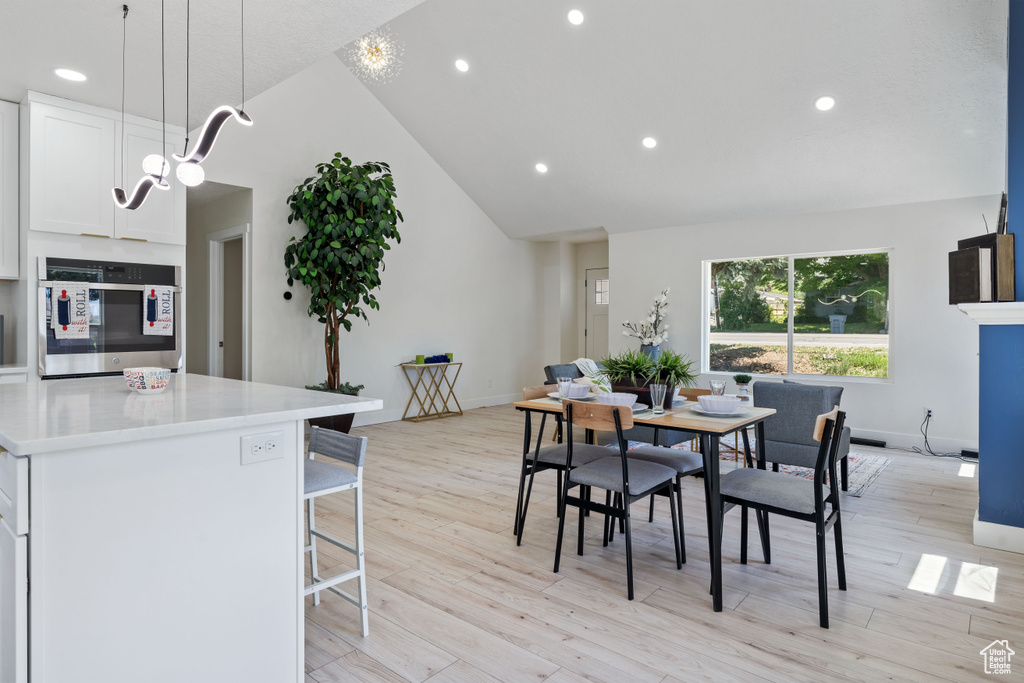 Dining space featuring recessed lighting, light wood-style floors, baseboards, and high vaulted ceiling