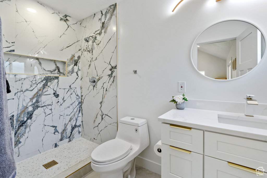 Bathroom with vanity, a marble finish shower, and toilet