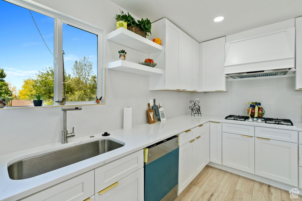Kitchen featuring dishwasher, a sink, custom exhaust hood, decorative backsplash, and recessed lighting