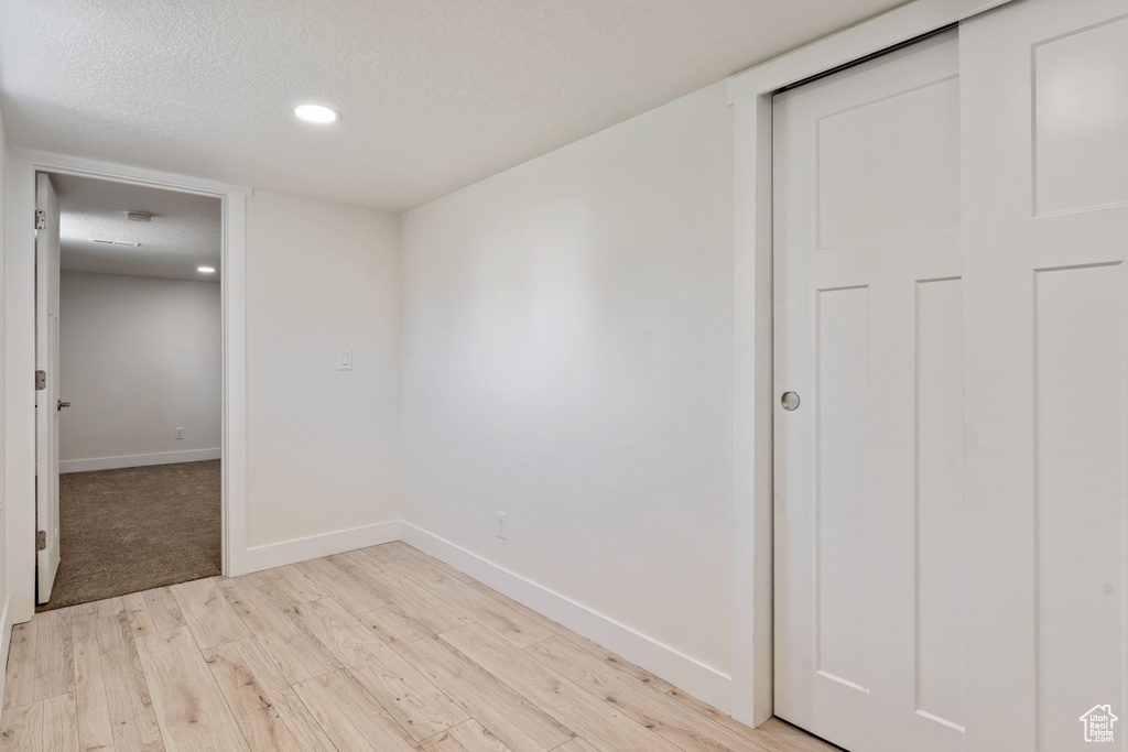 Unfurnished room featuring light wood-style flooring, baseboards, a textured ceiling, and recessed lighting