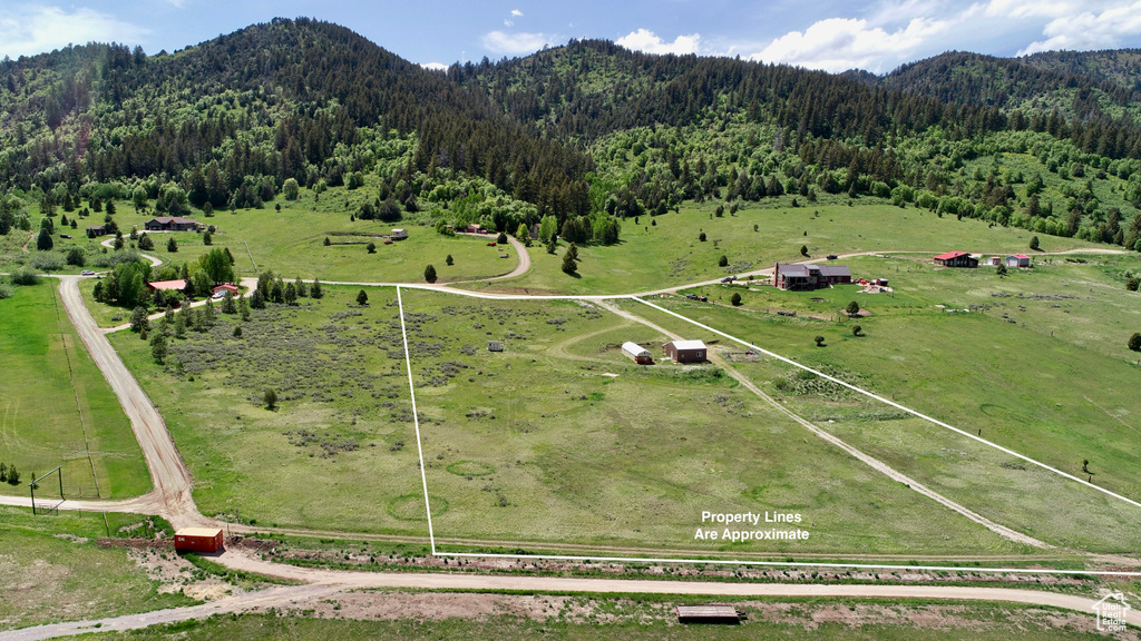 Overview of rural landscape featuring a heavily wooded area, a mountain backdrop, and a pastoral area
