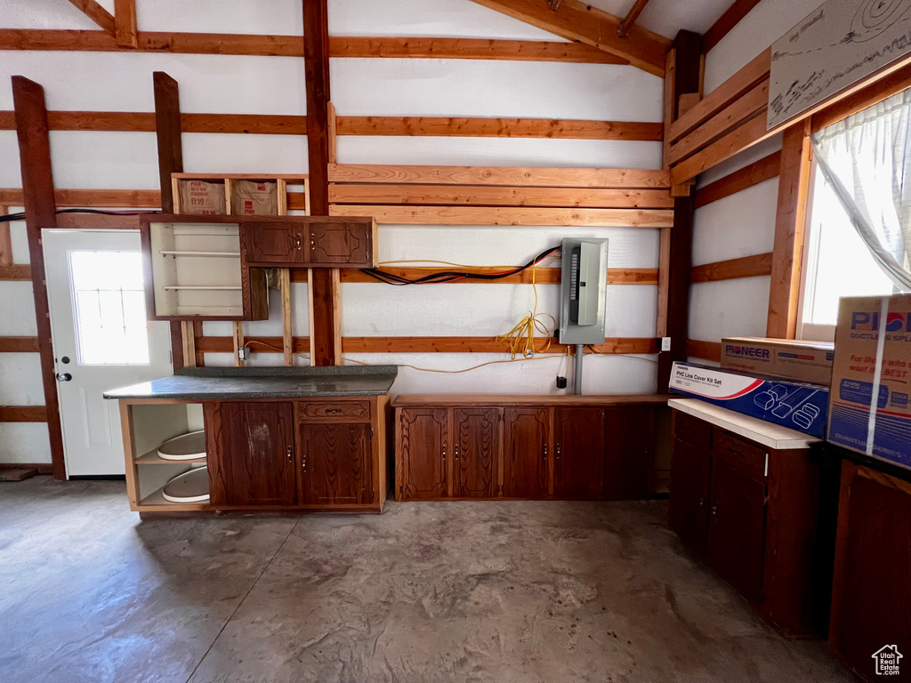 Kitchen with open shelves, unfinished concrete flooring, and electric panel