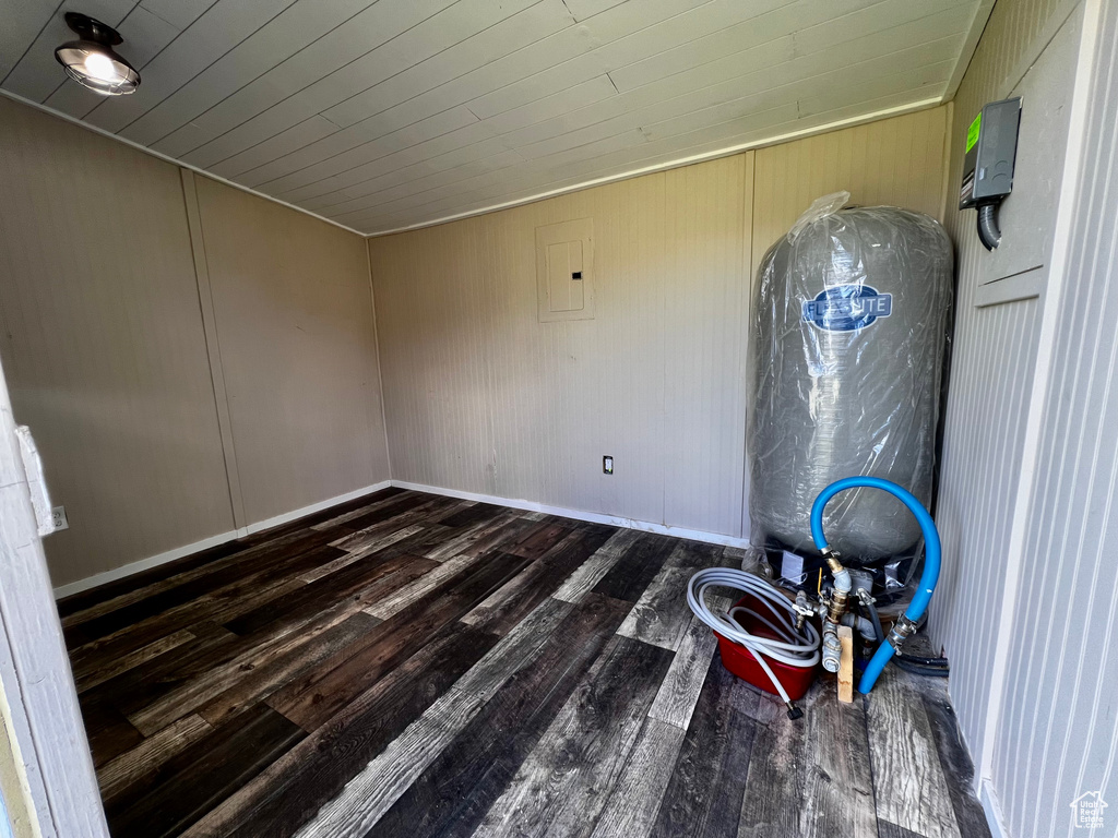 Unfurnished room featuring wood finished floors, baseboards, electric panel, and wooden ceiling