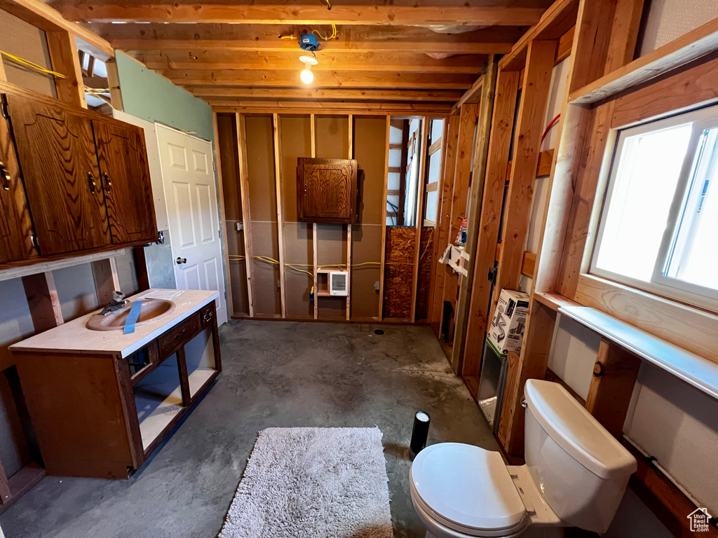 Bathroom with toilet, unfinished concrete flooring, and heating unit