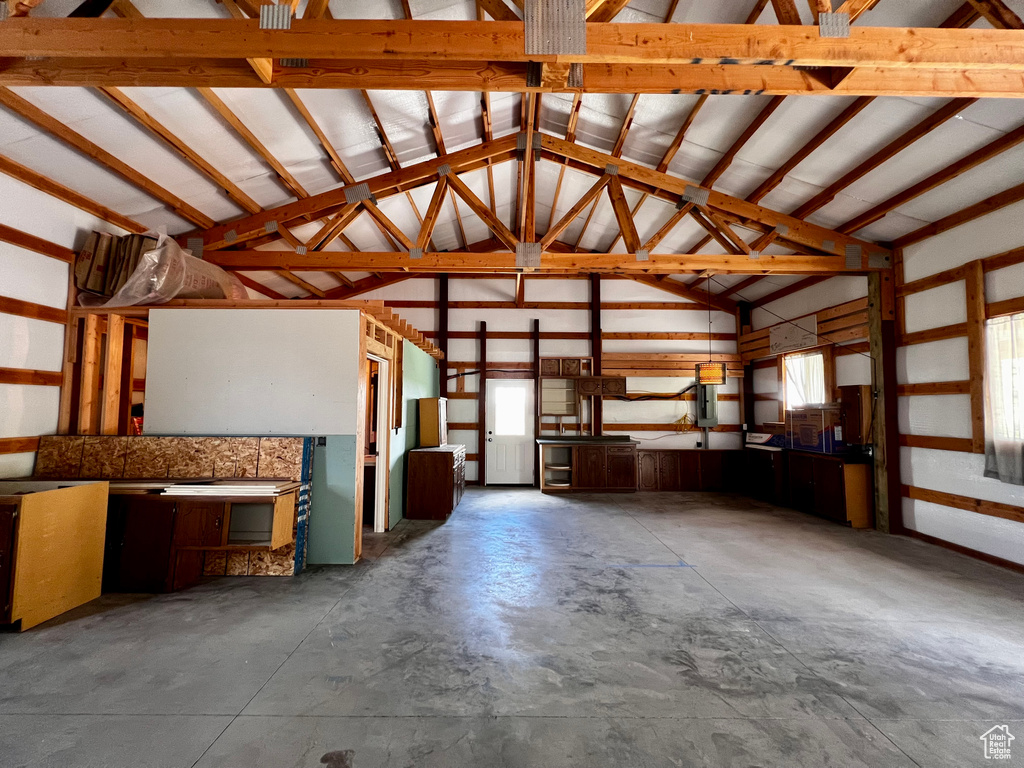 Miscellaneous room with lofted ceiling, unfinished concrete floors, and a garage