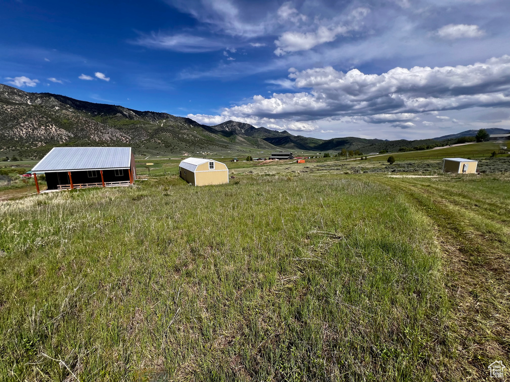 View of yard featuring an outdoor structure, a mountain view, a view of countryside, and a pole building
