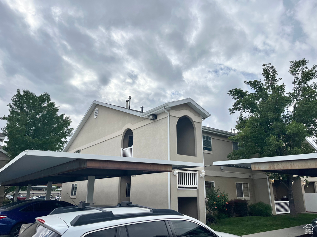 View of front of house with stucco siding and covered parking