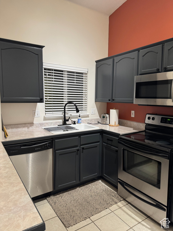 Kitchen with appliances with stainless steel finishes, a sink, light countertops, and light tile patterned floors