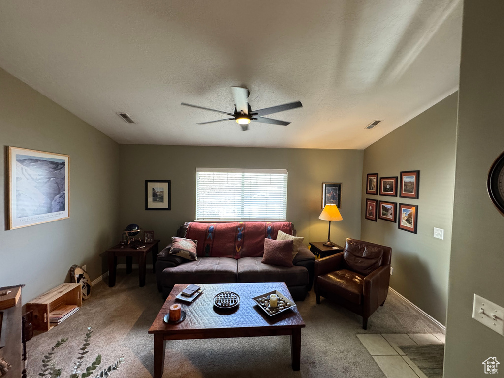 Carpeted living area featuring lofted ceiling, a ceiling fan, and baseboards