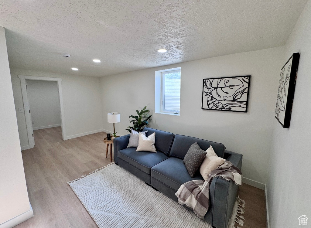 Living room featuring a textured ceiling, light wood-style floors, baseboards, and recessed lighting