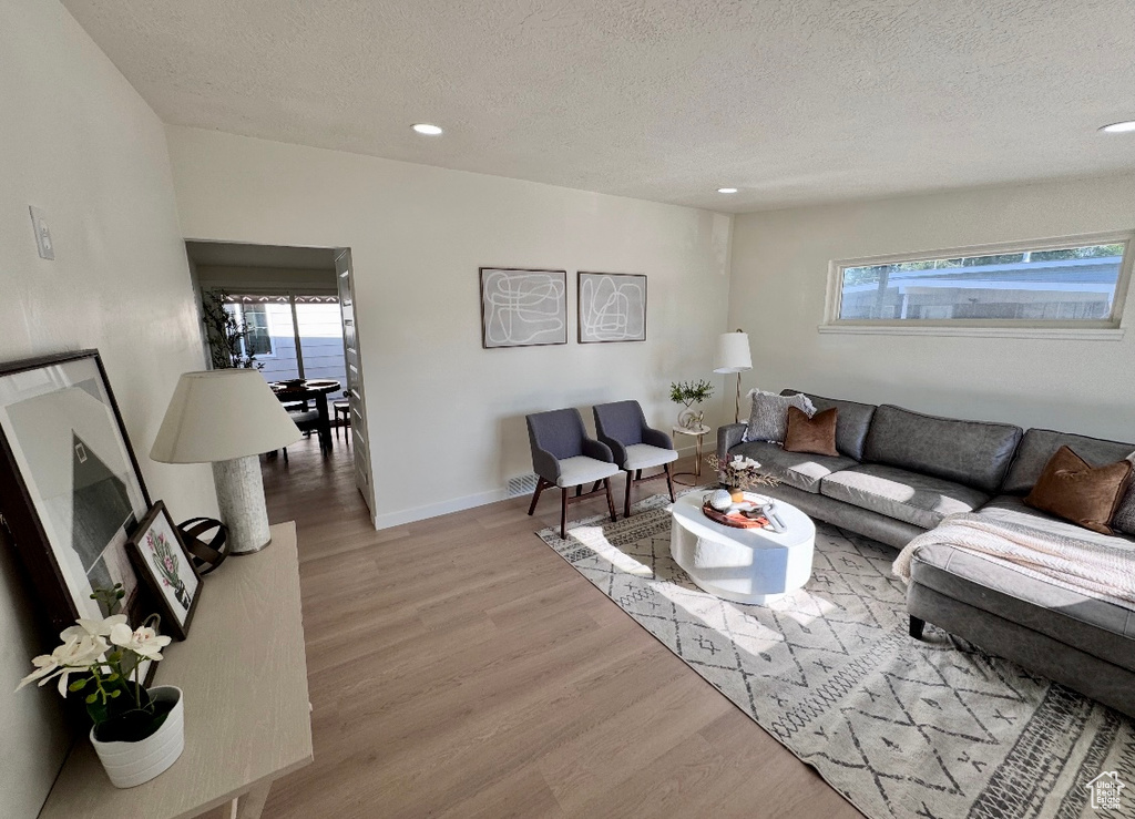Living area with a textured ceiling, wood finished floors, recessed lighting, and baseboards