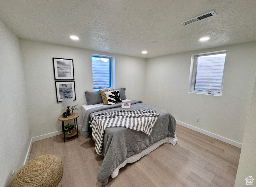 Bedroom with wood finished floors, baseboards, recessed lighting, and a textured ceiling