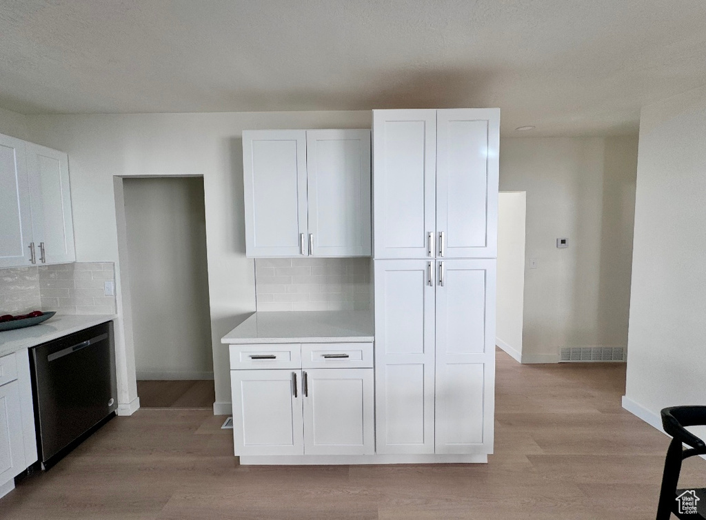 Kitchen featuring dishwasher, decorative backsplash, white cabinetry, light wood-style flooring, and light countertops