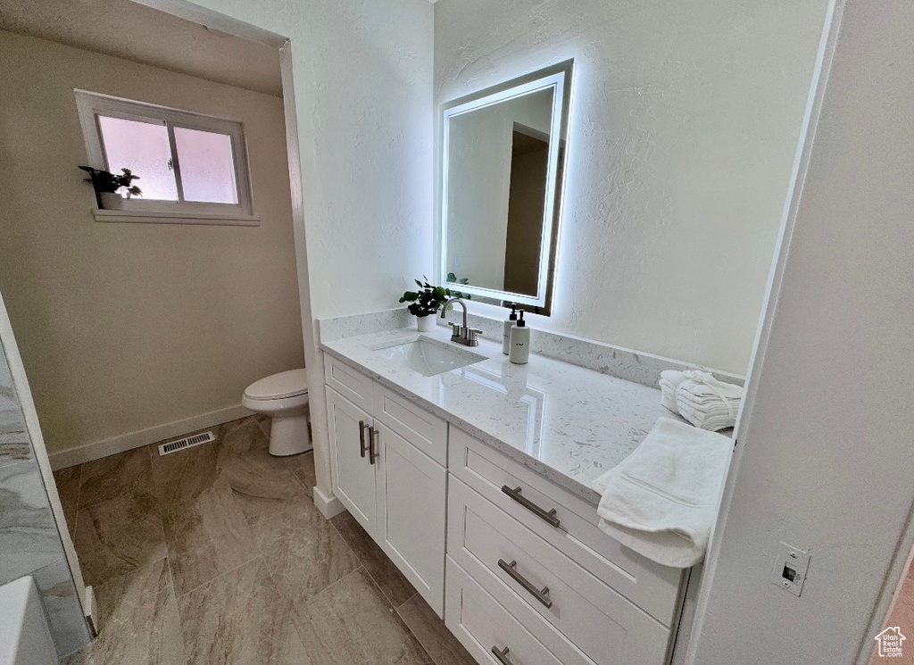 Bathroom featuring toilet, vanity, and baseboards