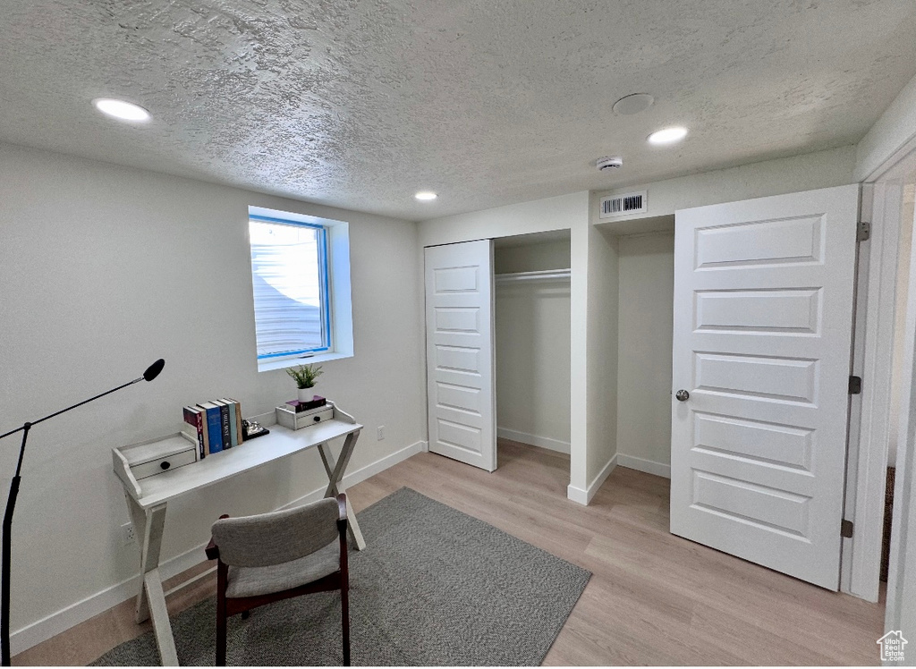 Home office featuring a textured ceiling, light wood-style flooring, recessed lighting, and baseboards