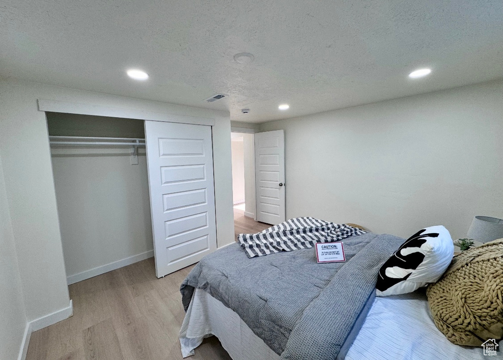 Bedroom featuring recessed lighting, light wood-style floors, a closet, baseboards, and a textured ceiling