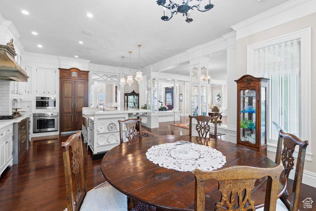 Dining space with dark wood-style flooring, crown molding, recessed lighting, a chandelier, and a decorative wall