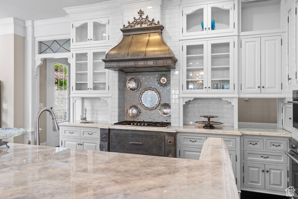 Kitchen featuring white cabinets, backsplash, and premium range hood