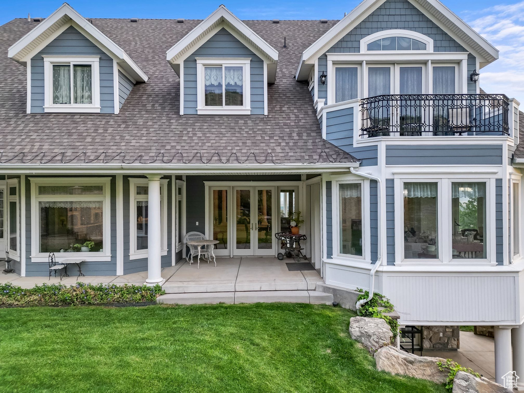 Back of property with french doors, a shingled roof, a balcony, and a yard