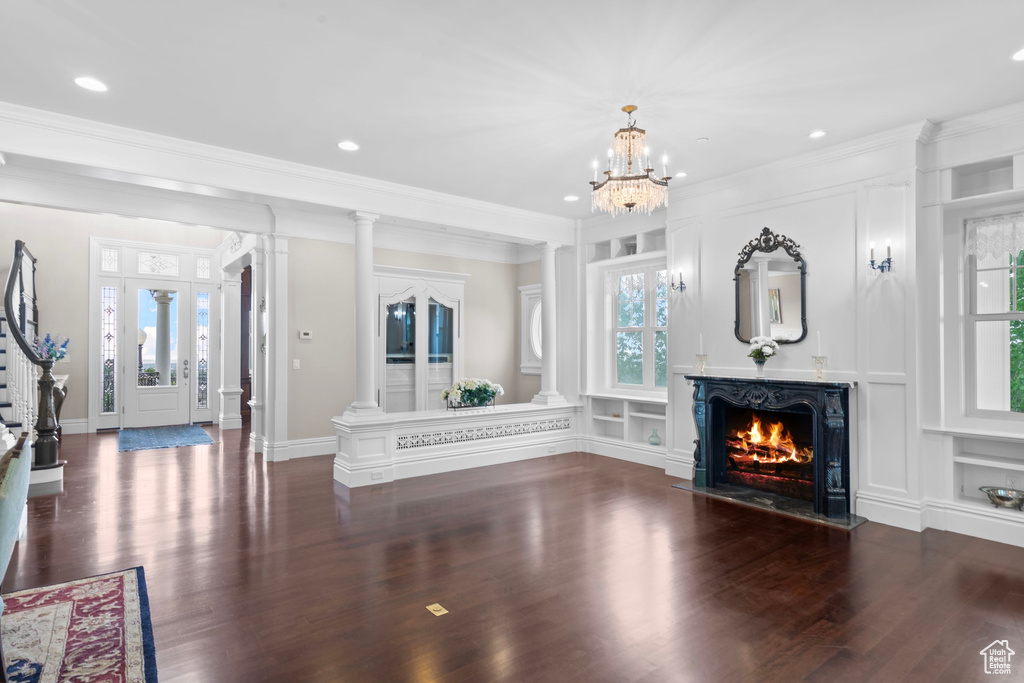 Unfurnished living room featuring wood finished floors, ornamental molding, a lit fireplace, recessed lighting, and a chandelier