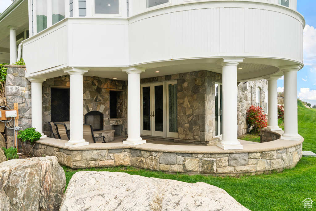 Back of property featuring stone siding, an outdoor stone fireplace, and french doors