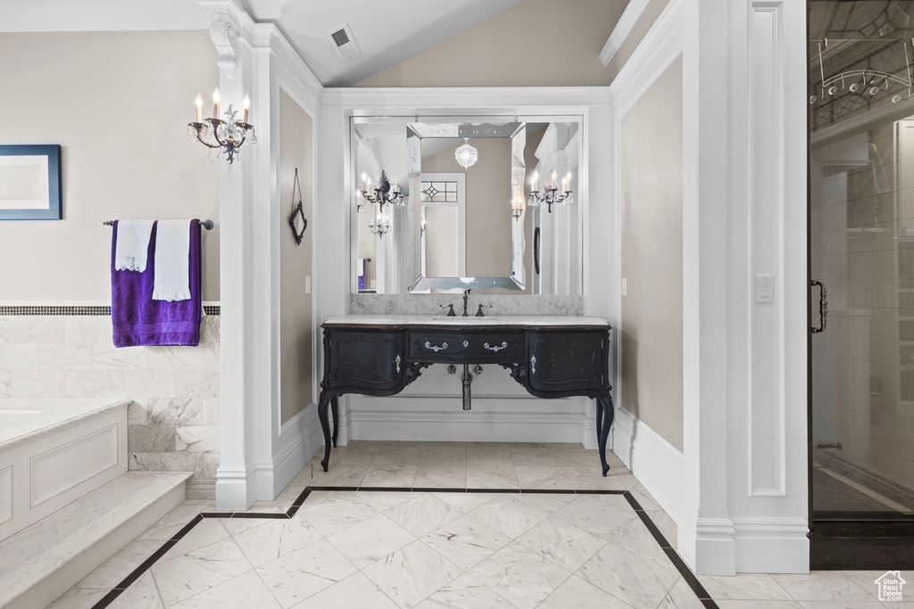 Bathroom featuring marble finish floors, a chandelier, a shower stall, wainscoting, and vaulted ceiling