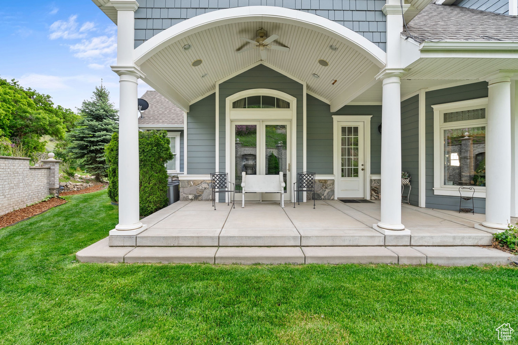 Doorway to property featuring a porch, a yard, and a shingled roof