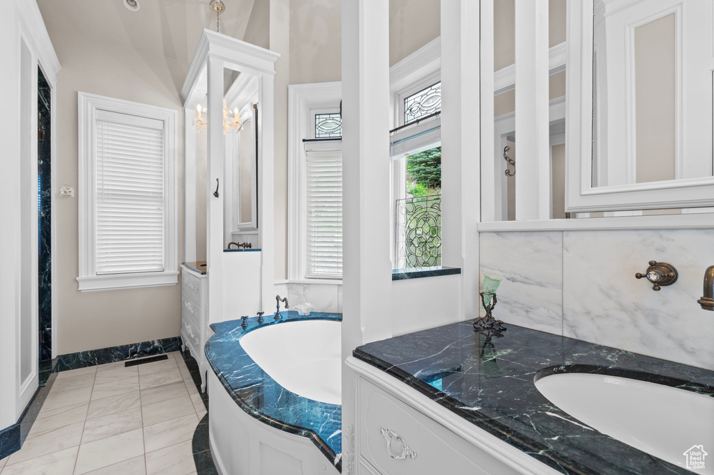 Bathroom with a garden tub, baseboards, vanity, and marble finish floors