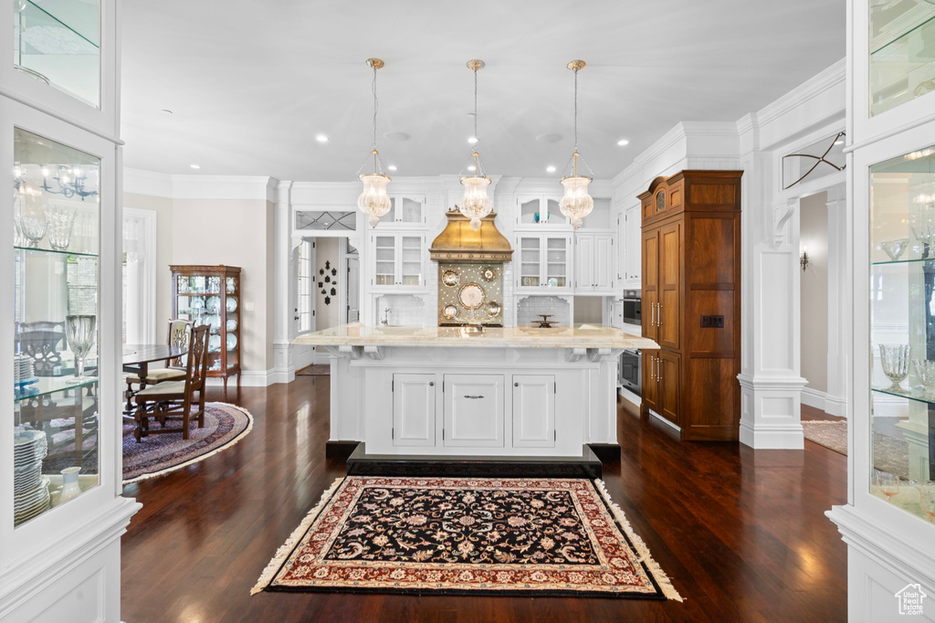 Kitchen featuring dark wood-type flooring, white cabinetry, oven, glass insert cabinets, and hanging light fixtures