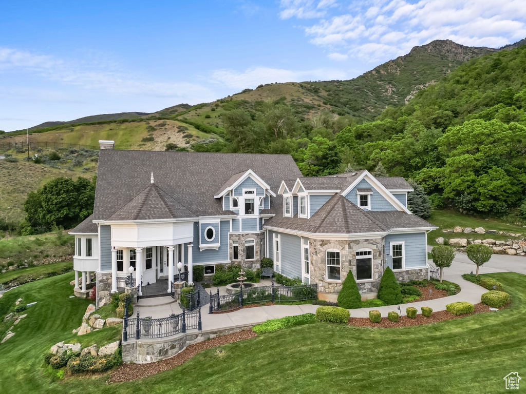 Rear view of property with stone siding, a mountain view, a gate, and a patio