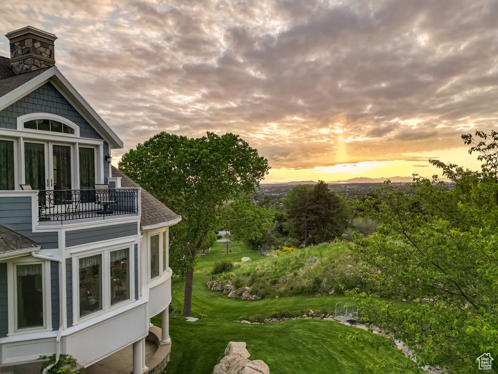 Yard at dusk with a balcony and a lawn