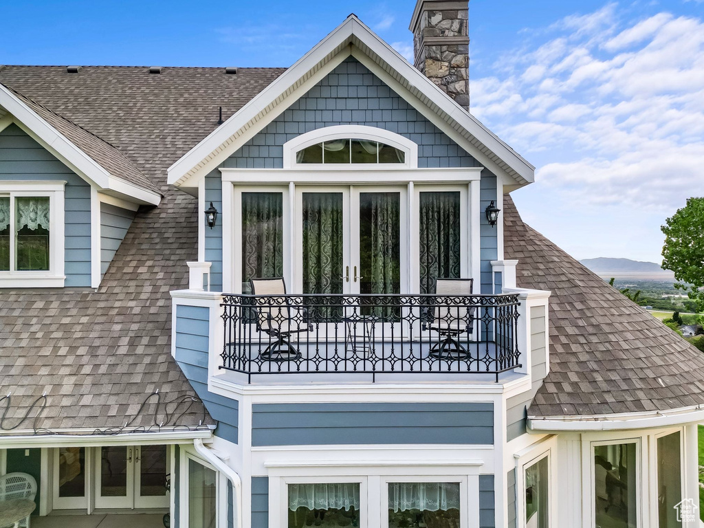 View of side of property with a balcony and roof with shingles