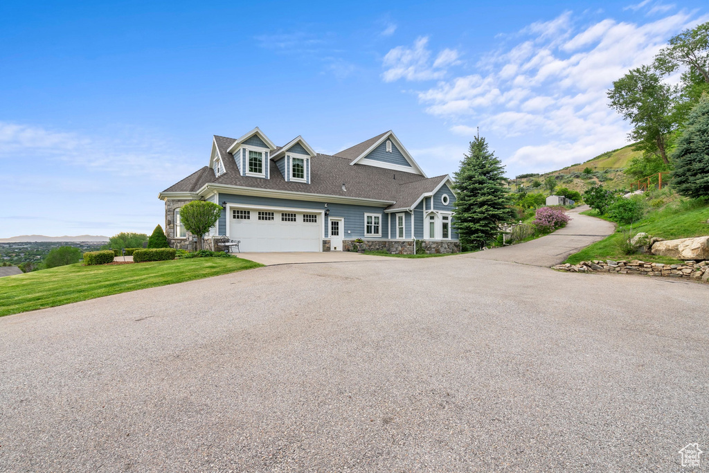 Shingle-style home with stone siding, driveway, and a front yard
