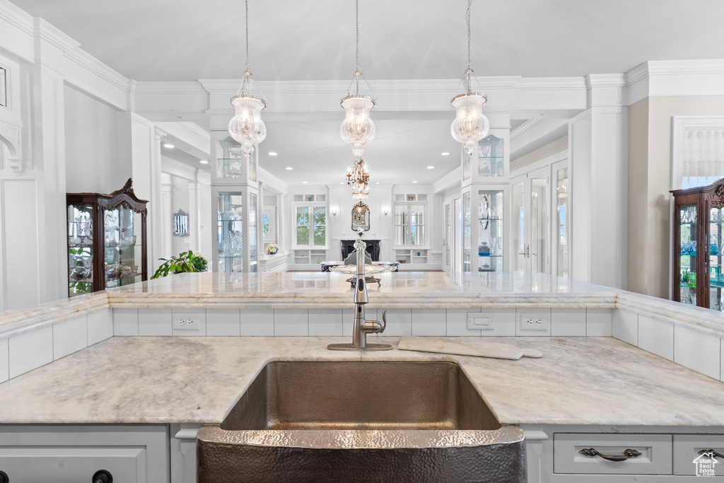 Kitchen featuring a sink, open floor plan, light stone counters, crown molding, and recessed lighting