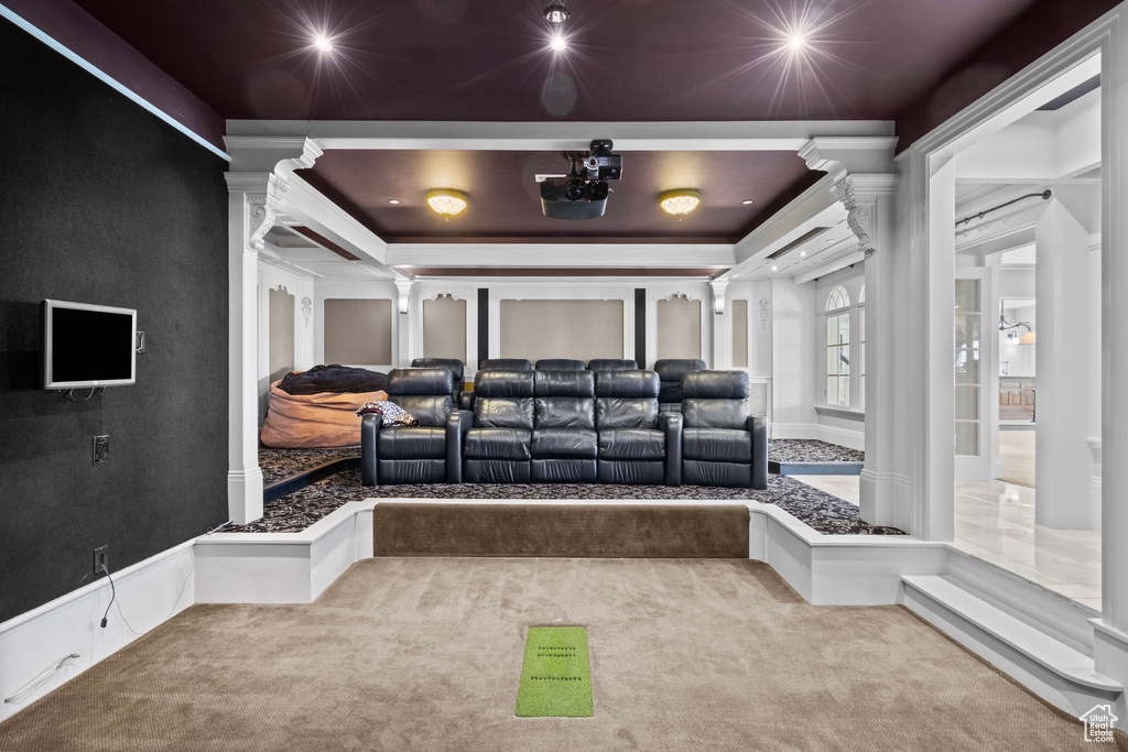 Carpeted home theater with ornate columns and ornamental molding