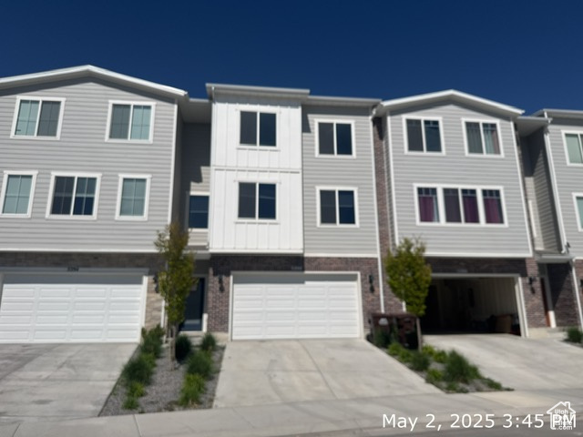 Townhome / multi-family property with a garage, concrete driveway, and board and batten siding